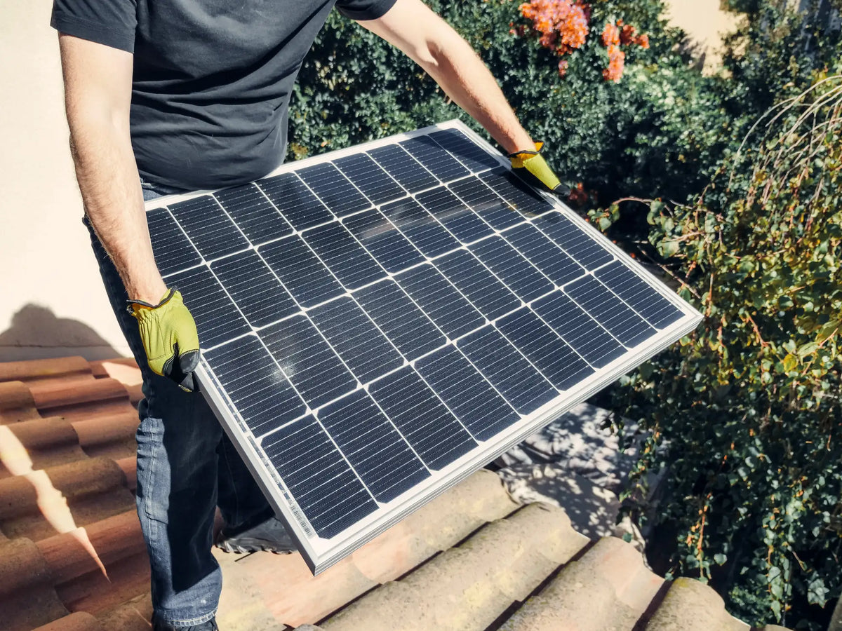 Ein Mann trägt ein kleines Solarpanel auf dem Dach