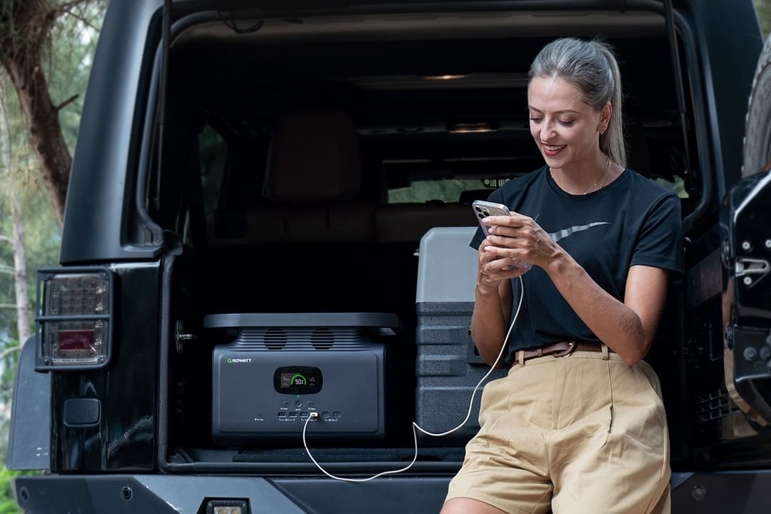 Eine Frau lädt ihr Handy mit Growatt Powerstation auf Reise